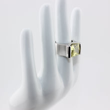 Silver ring with a green gemstone on a white hand model