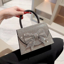 Handbag with a decorative bow held by a hand against a neutral background