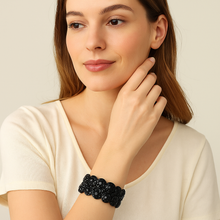 Woman wearing a black beaded bracelet on a neutral background