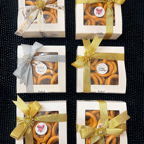 Five boxes of  taralli cookies  with decorative bows on a black textured background
