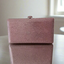 pink clutch bag on a reflective surface with a neutral background