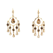 Gold chandelier earrings with brown and clear gemstones on a white background