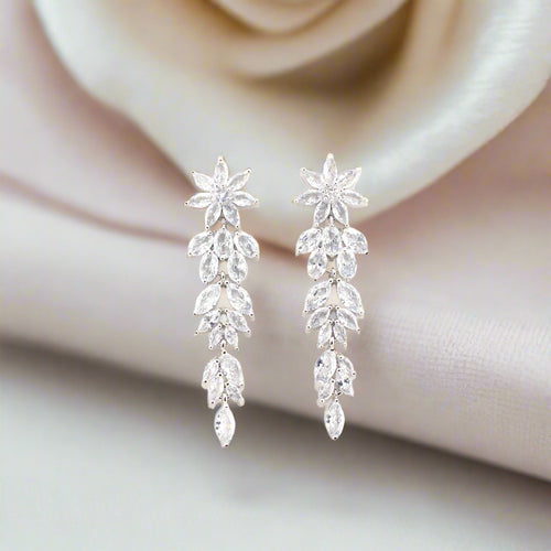 Silver earrings with clear stones on a soft fabric background