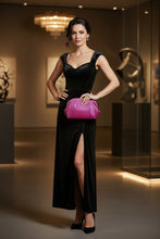 A hand holding a metallic magenta pink pleated clutch purse with a small gold clasp, set against a background of vertical gold panels with warm lighting.