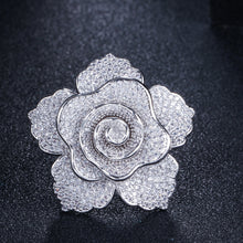 Silver rose-shaped jewelry piece on a dark textured background