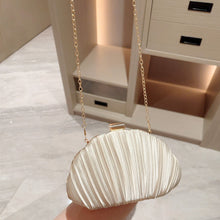 Shell-shaped handbag with a gold chain on a marble surface