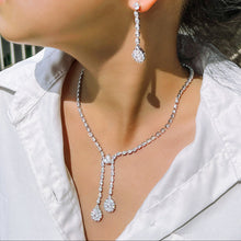 Close-up of a person wearing a silver necklace and earrings.