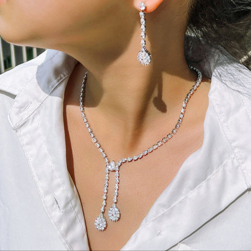 Close-up of a person wearing a silver necklace and earrings.