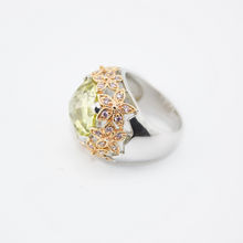 Silver ring with a green gemstone and gold accents on a white background