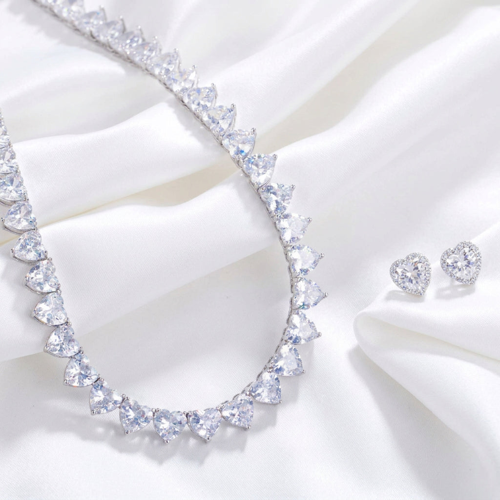 A heart-shaped crystal necklace with matching heart-shaped earrings displayed on a dark velvet surface.