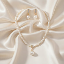 Pearl necklace and earrings set on a black mannequin bust.