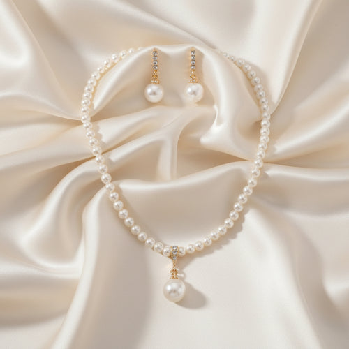 Pearl necklace and earrings set on a black mannequin bust.