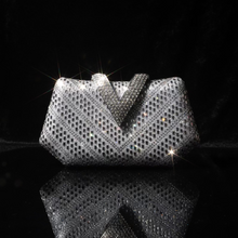 A silver rhinestone-embellished clutch bag with a prominent V-shaped top detail, displayed on a white surface against a white background.
