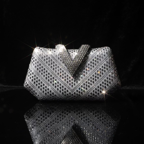A silver rhinestone-embellished clutch bag with a prominent V-shaped top detail, displayed on a white surface against a white background.